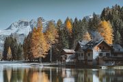 A photograph of a lake below snow peaks and autumn larches.