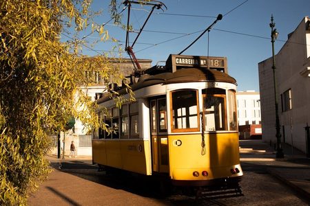 A photograph of a yellow tram on a sunlit street.