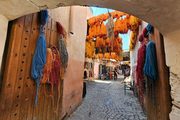 A photograph of dyed yarn hanging over a market alley.